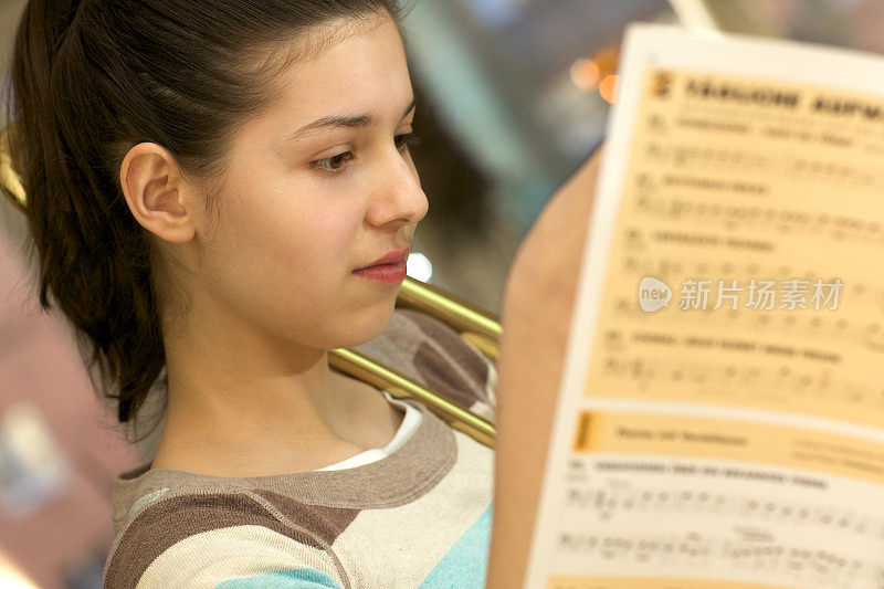 少女练习长号，研究音乐记谱法
