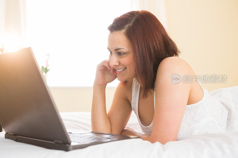 穿着睡衣用笔记本电脑的快乐女人