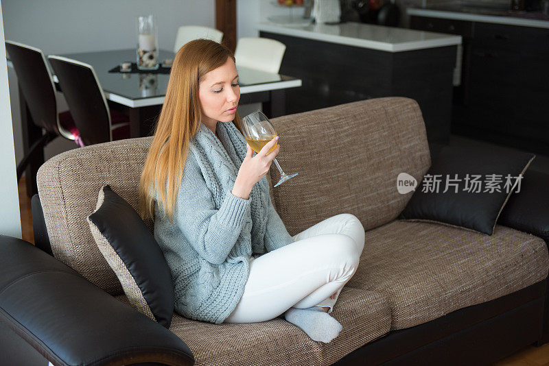 单身女人坐在沙发上喝着白葡萄酒