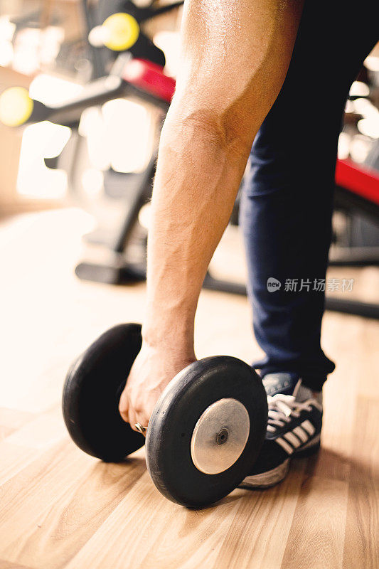 肌肉发达的人在健身房用哑铃锻炼