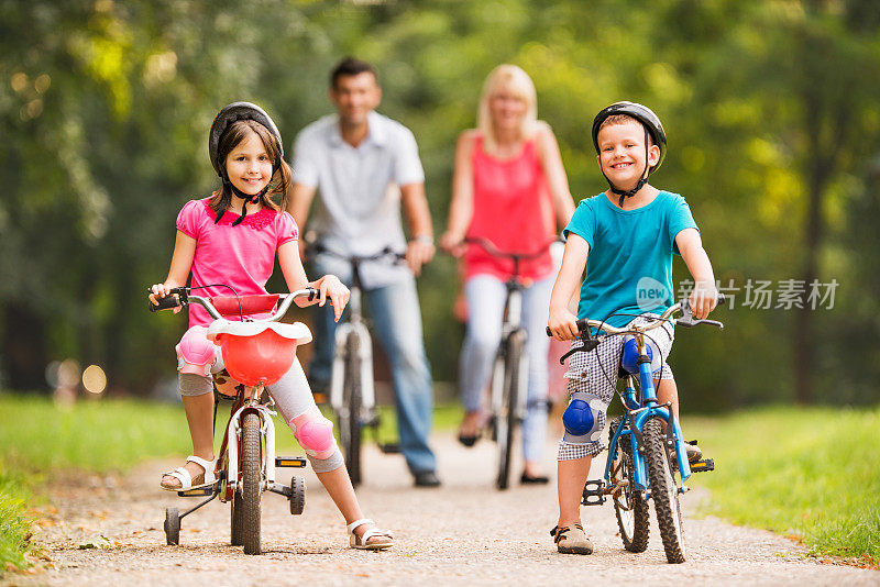 孩子们和父母在公园里骑自行车。