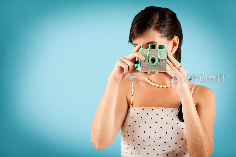 彩色照片的复古年轻女人拿着一个古董相机