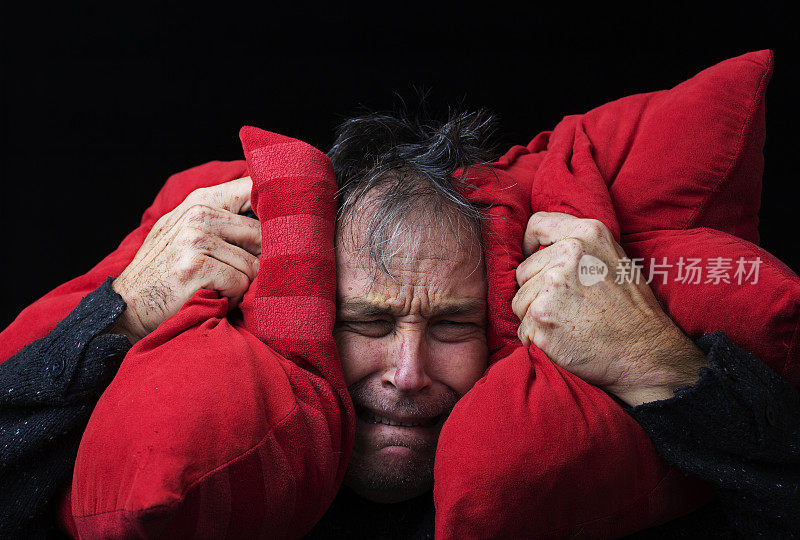 男人把枕头放在耳朵上以阻止噪音