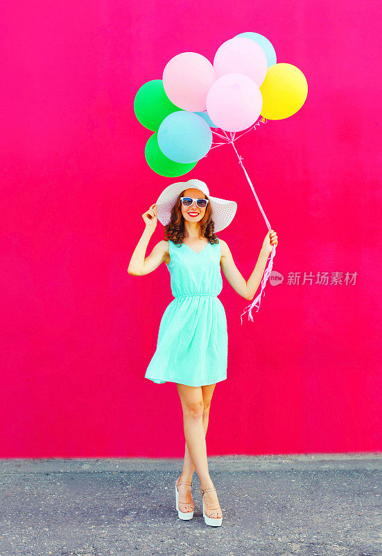 快乐微笑的女人与一个空气彩色气球是走过一个粉红色的背景