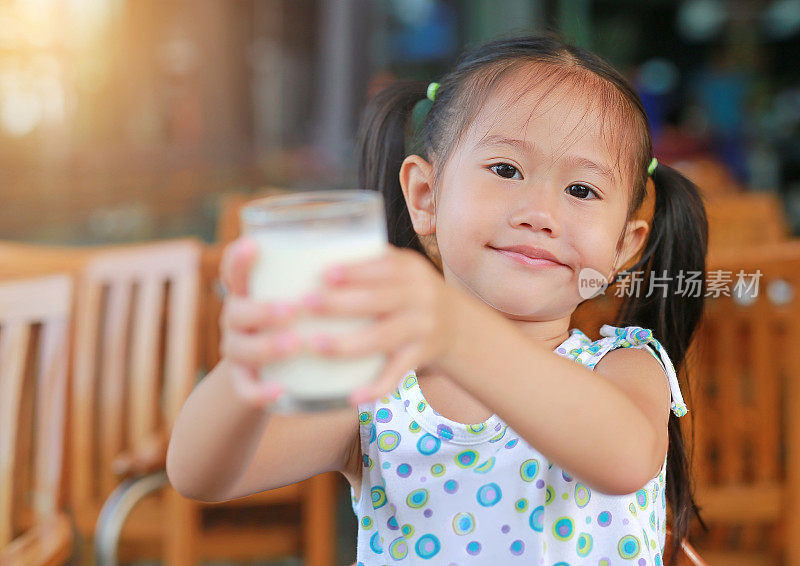 早上在餐厅微笑的亚洲女孩给你一杯牛奶。健康早餐理念。