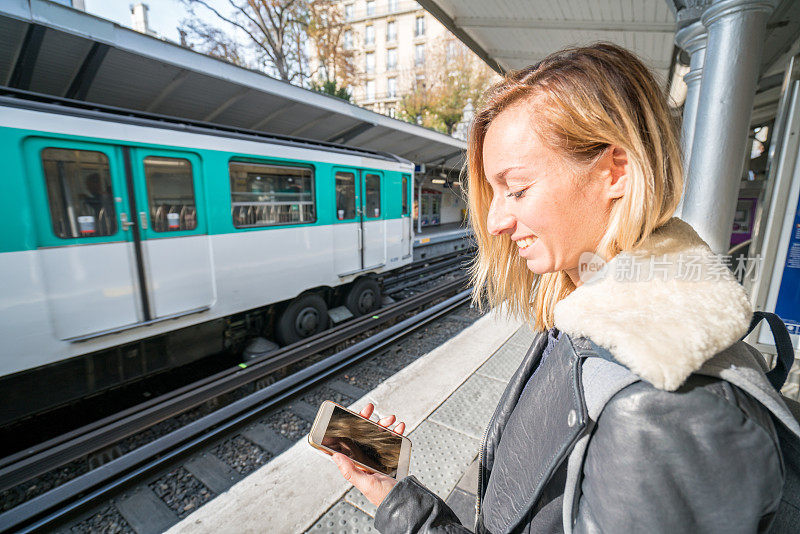 在巴黎等地铁的女孩，用手机发短信