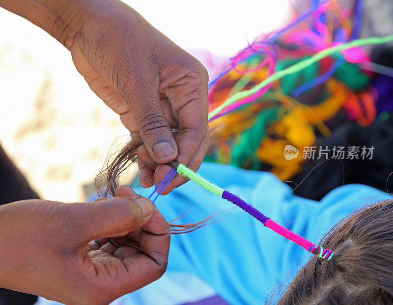 一个非洲妇女的手用一个小女孩的头发缠在一起