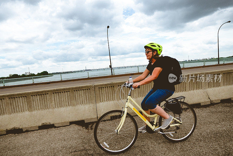 中年白人妇女微笑和骑自行车在加拿大魁北克蒙特利尔