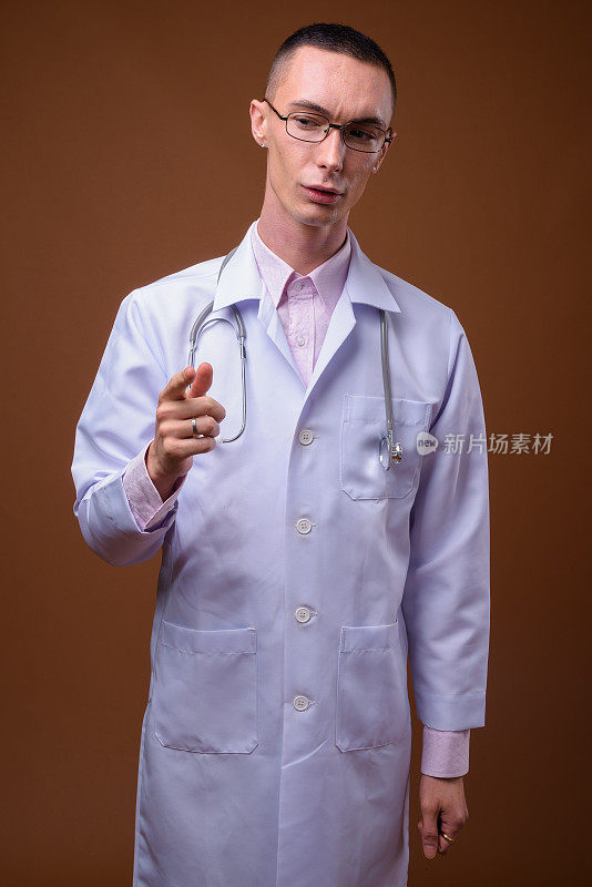 工作室拍摄的年轻英俊的男医生戴着眼镜，以有色的背景