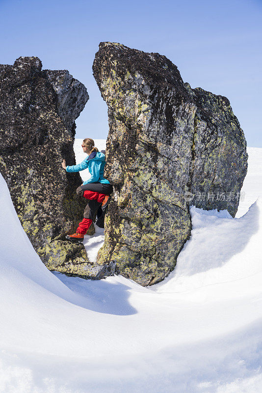 一名BC滑雪者在欧洲挪威哈当厄飞机上探索被雪覆盖的岩石