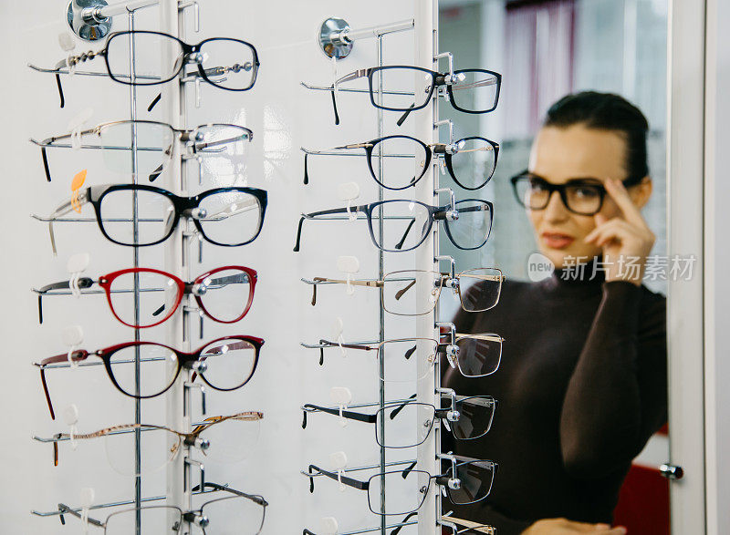 在眼镜店挑选眼镜的漂亮女人。视力矫正。眼科。有选择性的重点