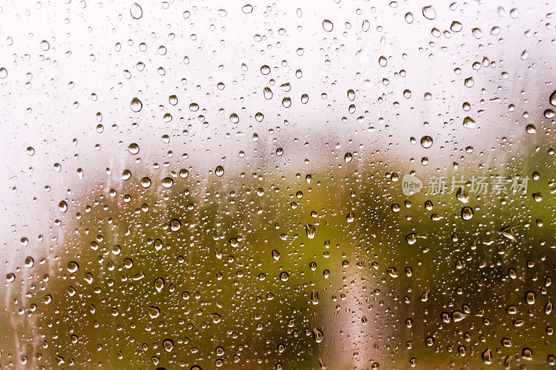 水滴的纹理顺着窗玻璃流下。雨滴落在汽车玻璃背景上，照片模糊，对焦柔和