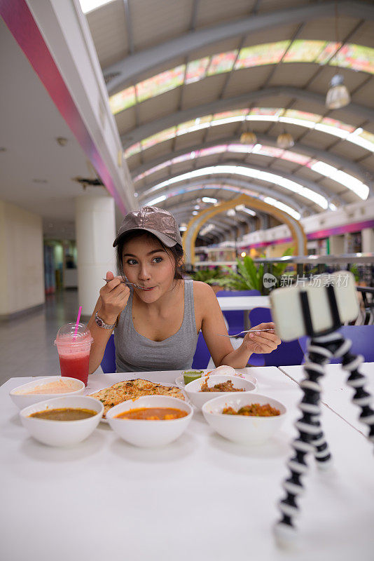 年轻美丽的亚洲女游客在餐厅享受印度美食的肖像