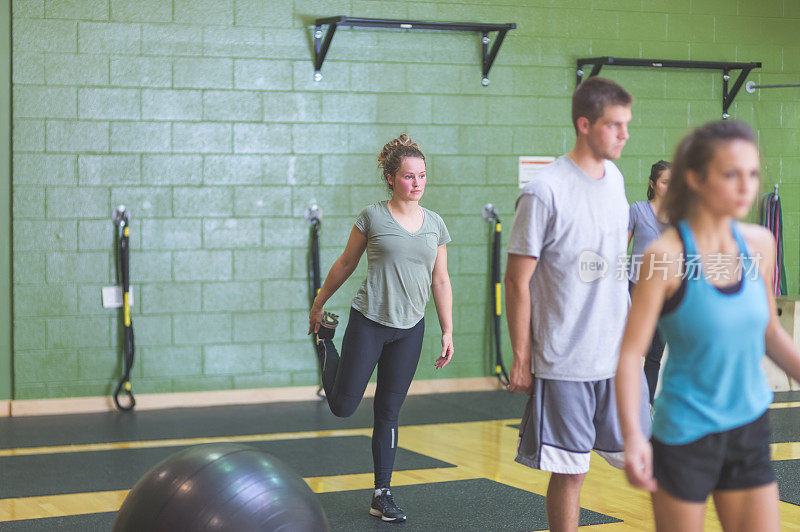 一群男女混合的大学生在一个现代化的健身设施里一起锻炼