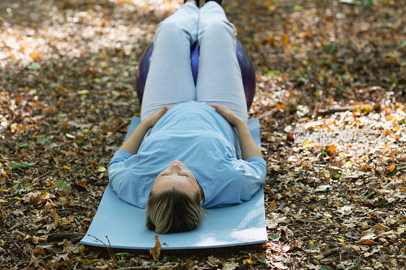 健康怀孕:金发女人在森林户外练习瑜伽