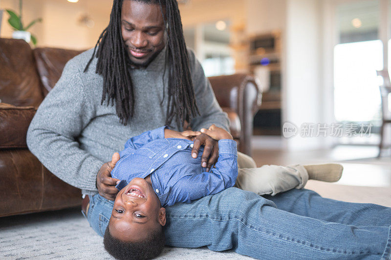 一位非裔美国父亲在客厅给儿子挠痒痒