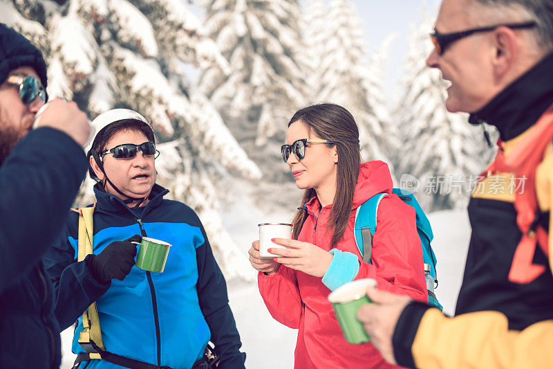 雪上徒步旅行的一群人在徒步旅行休息期间喝热茶