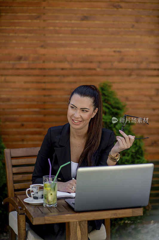 年轻的女商人在café用笔记本电脑工作