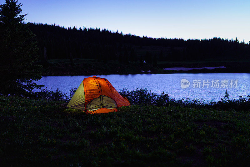 黄昏山湖上发光的帐篷