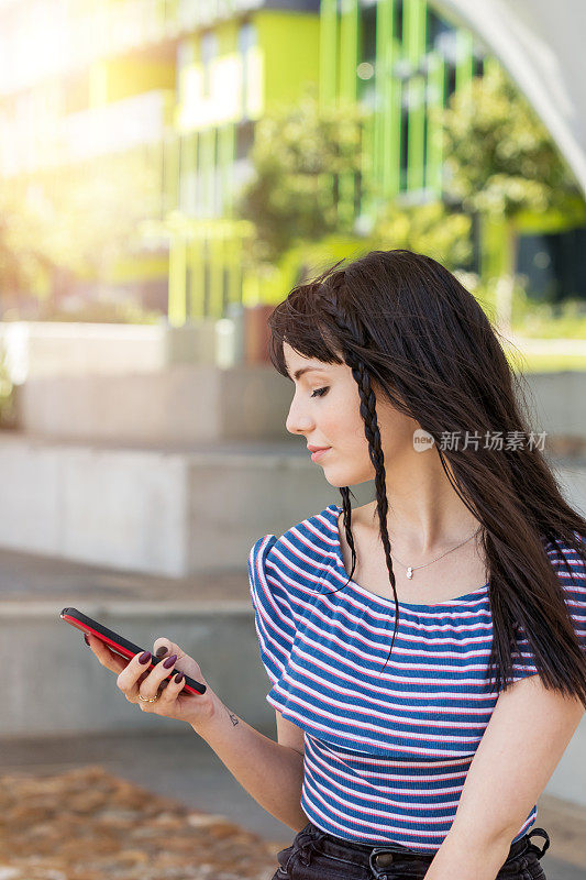 年轻女子在城市公园使用手机