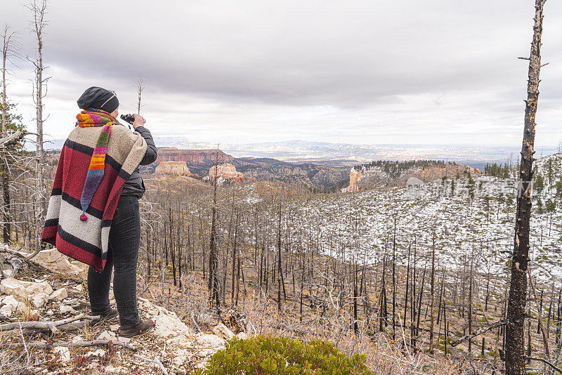 成熟快乐，身体积极，45岁的白人女性用智能手机拍摄被野火破坏的森林，在美国犹他州的布莱斯峡谷国家公园，在深秋。