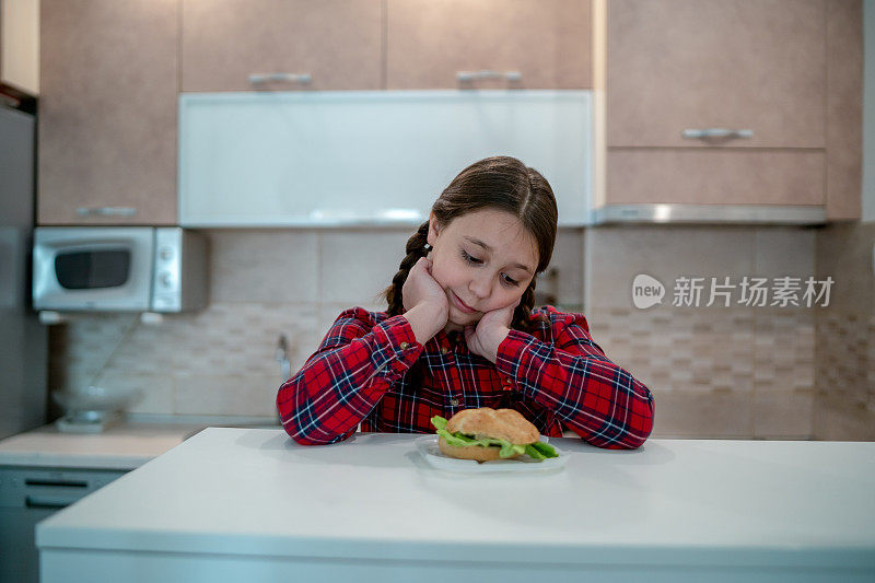 十几岁的女孩看着开胃的汉堡躺在她面前的桌子上