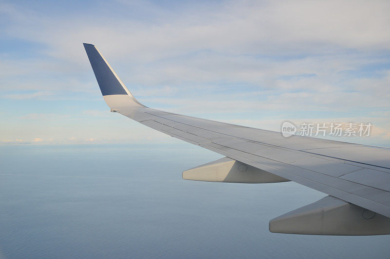 当飞机飞过海洋时，从窗口看到的机翼。
