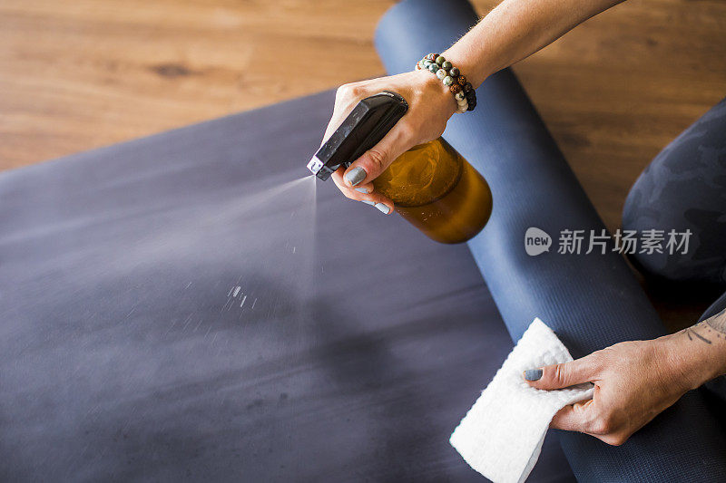 女人用消毒液清洁瑜伽垫。