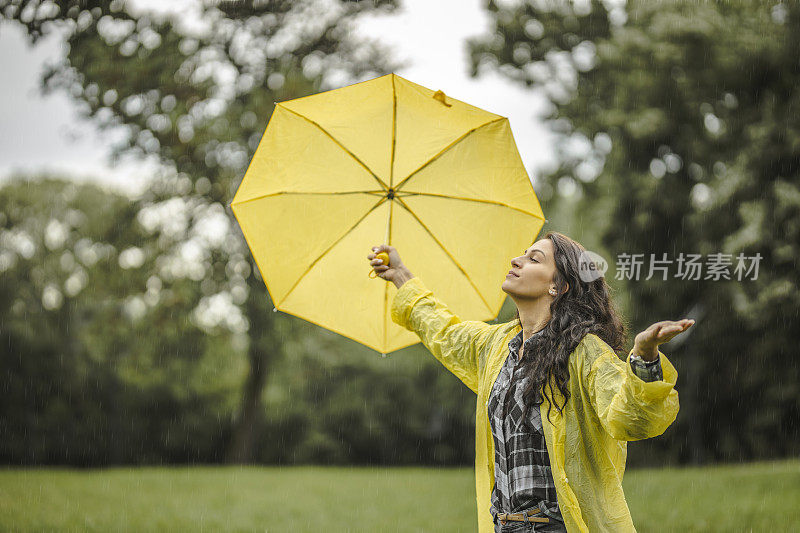 拿着黄伞，穿着黄雨衣，享受着雨的女人