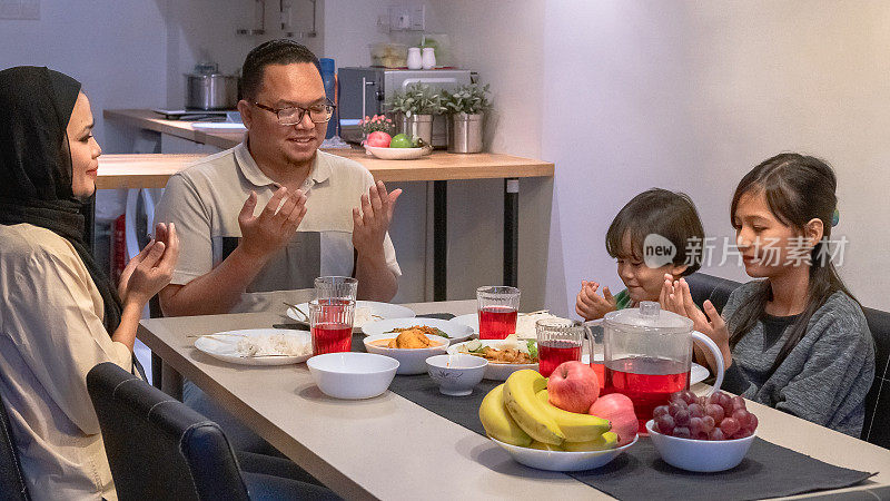 中镜头的马来西亚马来西亚家庭在餐桌前doa开始用餐。
