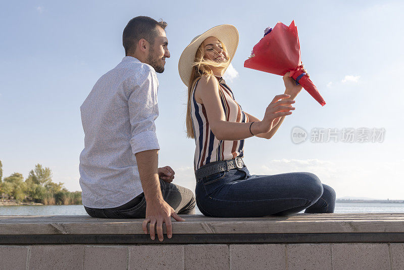 那个快乐的男人在公园里给一个女人送花。一个男人在一个夏日给他的爱人送花的照片。浪漫的情侣