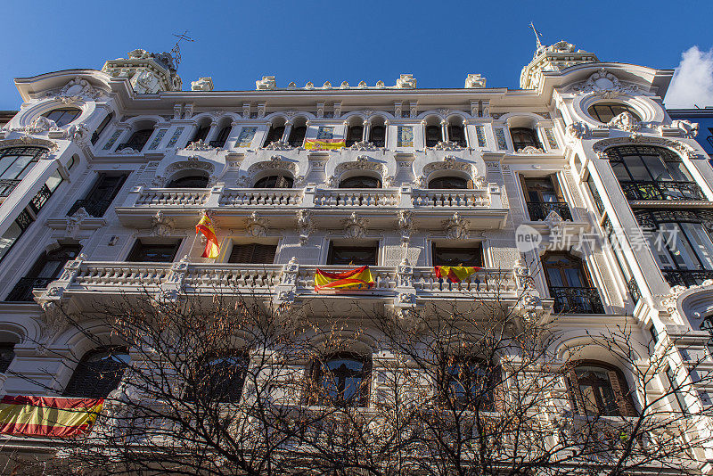 西班牙马德里市中心阳台上的经典建筑和西班牙国旗的正面上部。