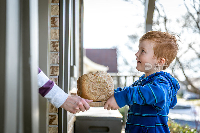 一个可爱的红发小孩把自制的面包送到邻居家