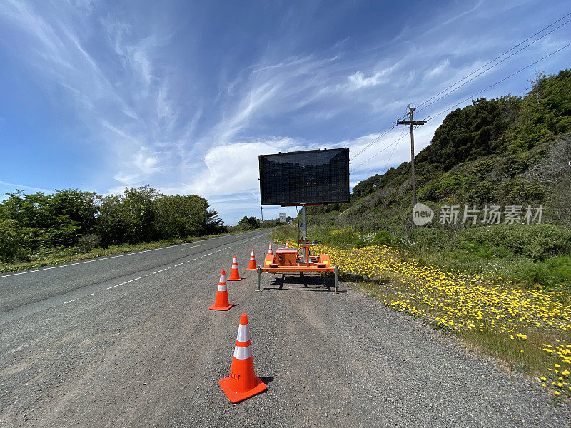 路边标志:悬挂在路边的橙色锥形移动警告标志，上面写着安全字样