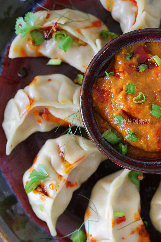 这是蒸过的馍馍(南亚饺子)，用白面粉和水面团填满鸡肉和什锦蔬菜，淋上辣椒油，放在盘子里，周围是用橙子辣酱做的小模子