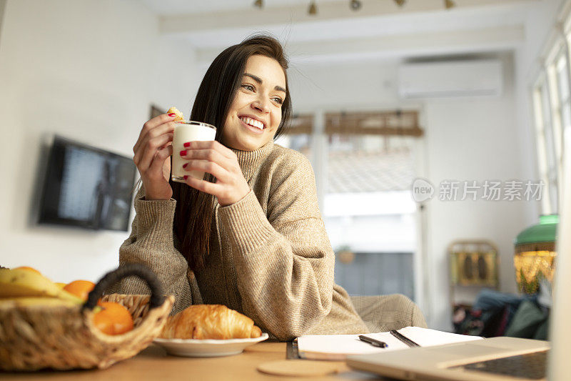 微笑的年轻女人在工作吃早餐