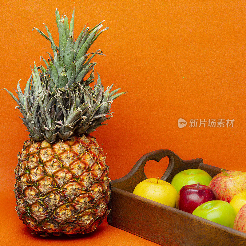 菠萝和苹果在橙色的背景