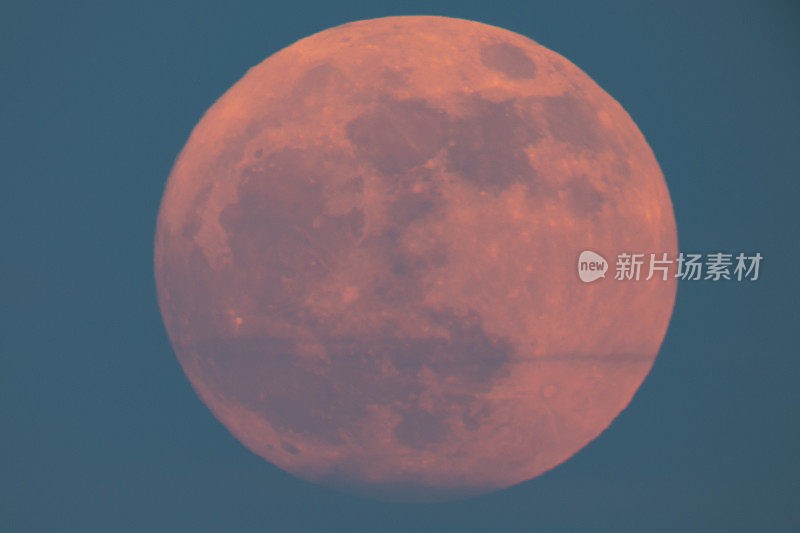超级草莓月亮升起在海面上，一个红色的满月在夏夜升起在海面上。满月