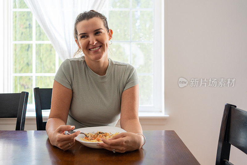 一位拉丁妇女正在家里吃一顿健康的饭