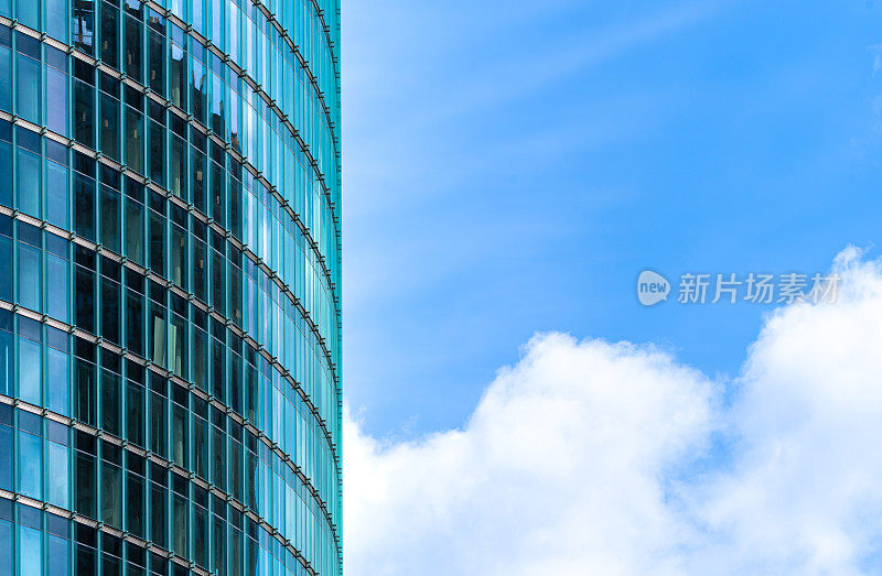 现代建筑的低角度视角，玻璃立面对着多云的天空