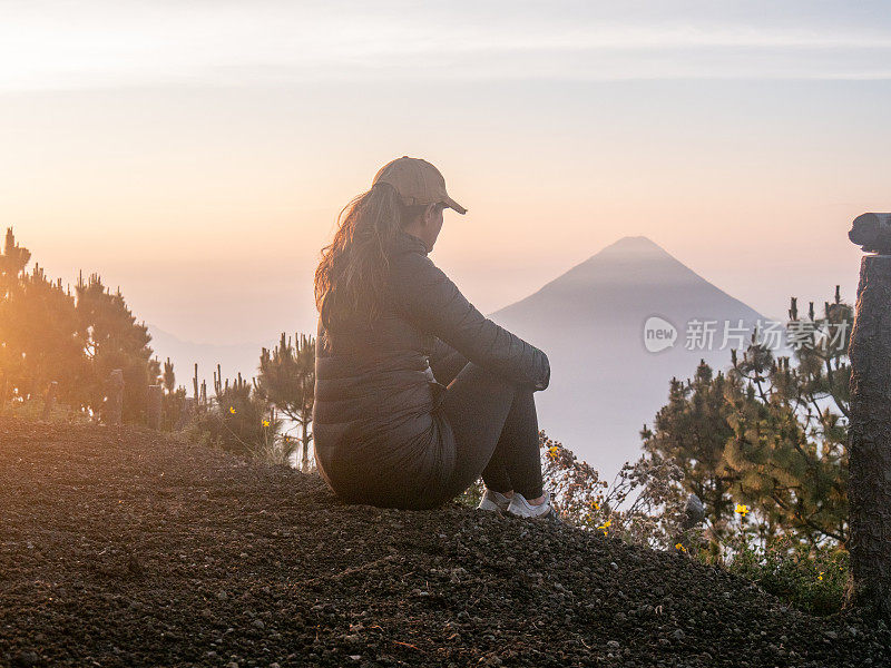 年轻女子在日出时凝视火山