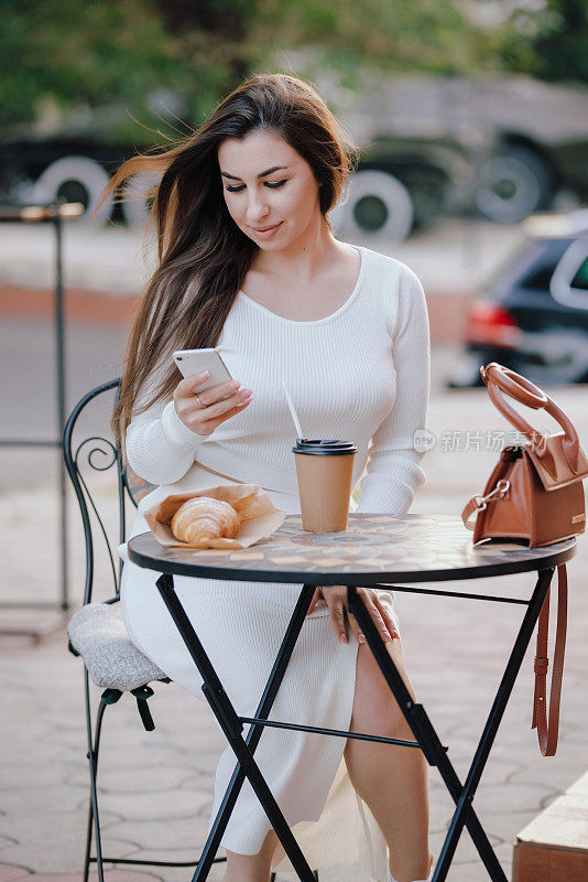 坐在户外咖啡馆玩智能手机的女人
