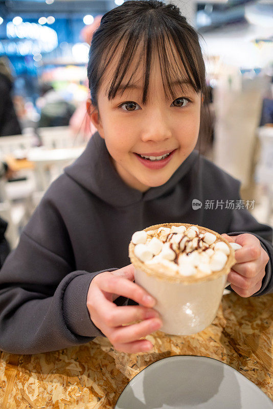 在咖啡馆里，十几岁的女孩拿着一杯咖啡的肖像——高视角