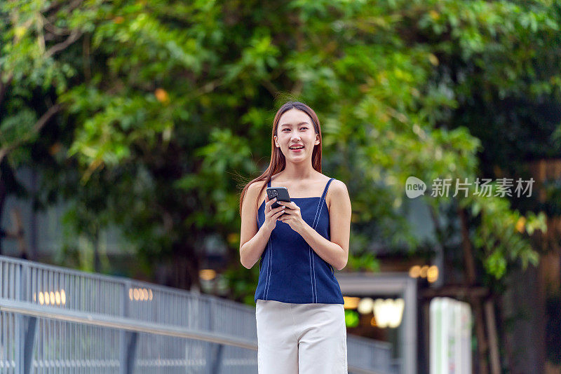 年轻的亚洲女性在移动中使用手机，在户外无缝地利用无线技术