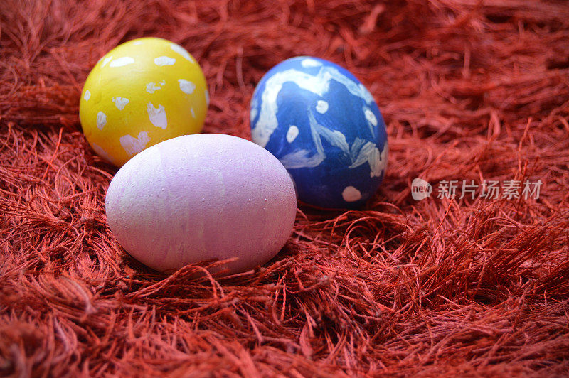 彩色手绘黄色，蓝色和粉红色华丽的复活节彩蛋鲜艳鲜艳的红色栗色地毯或地毯背景的复活节假期庆祝活动与复制空间