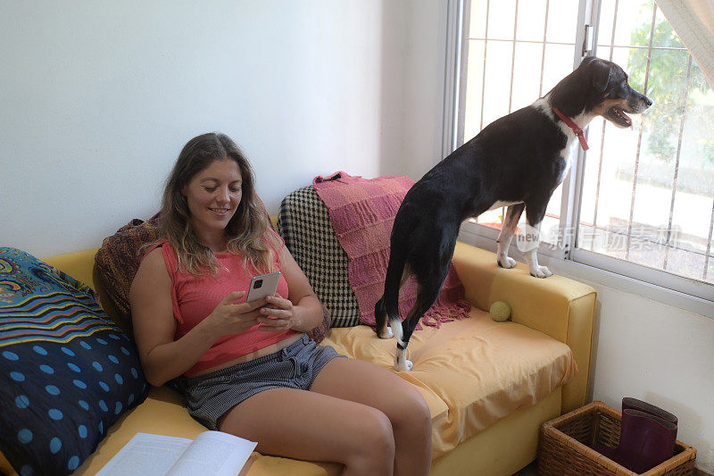 一个女人和她的狗在沙发上看她的手机