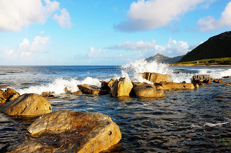 在美丽的夏日，海浪拍打着海滩附近的岩石