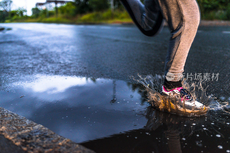 在雨天，年轻女子在沥青操场上跑步