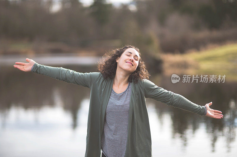 年轻的妈妈在湖边做瑜伽