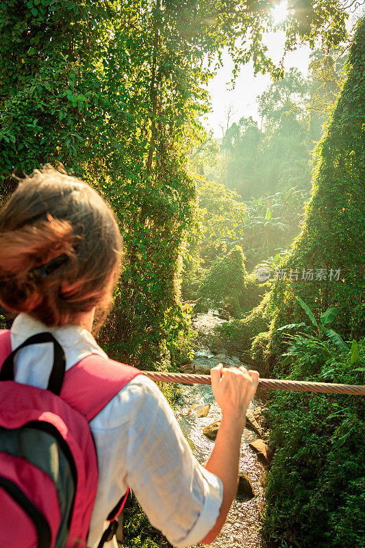 在热带雨林的吊桥上背着背包的女人